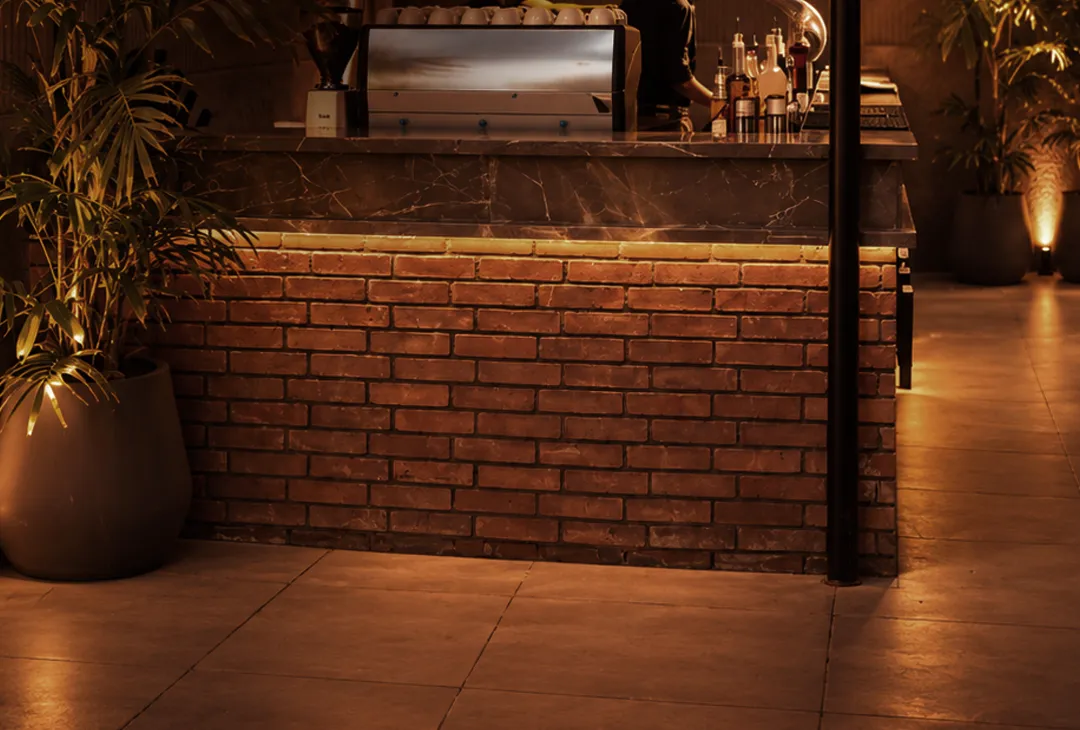 Brick bar counter lit warm at night with glasses hanging overhead
