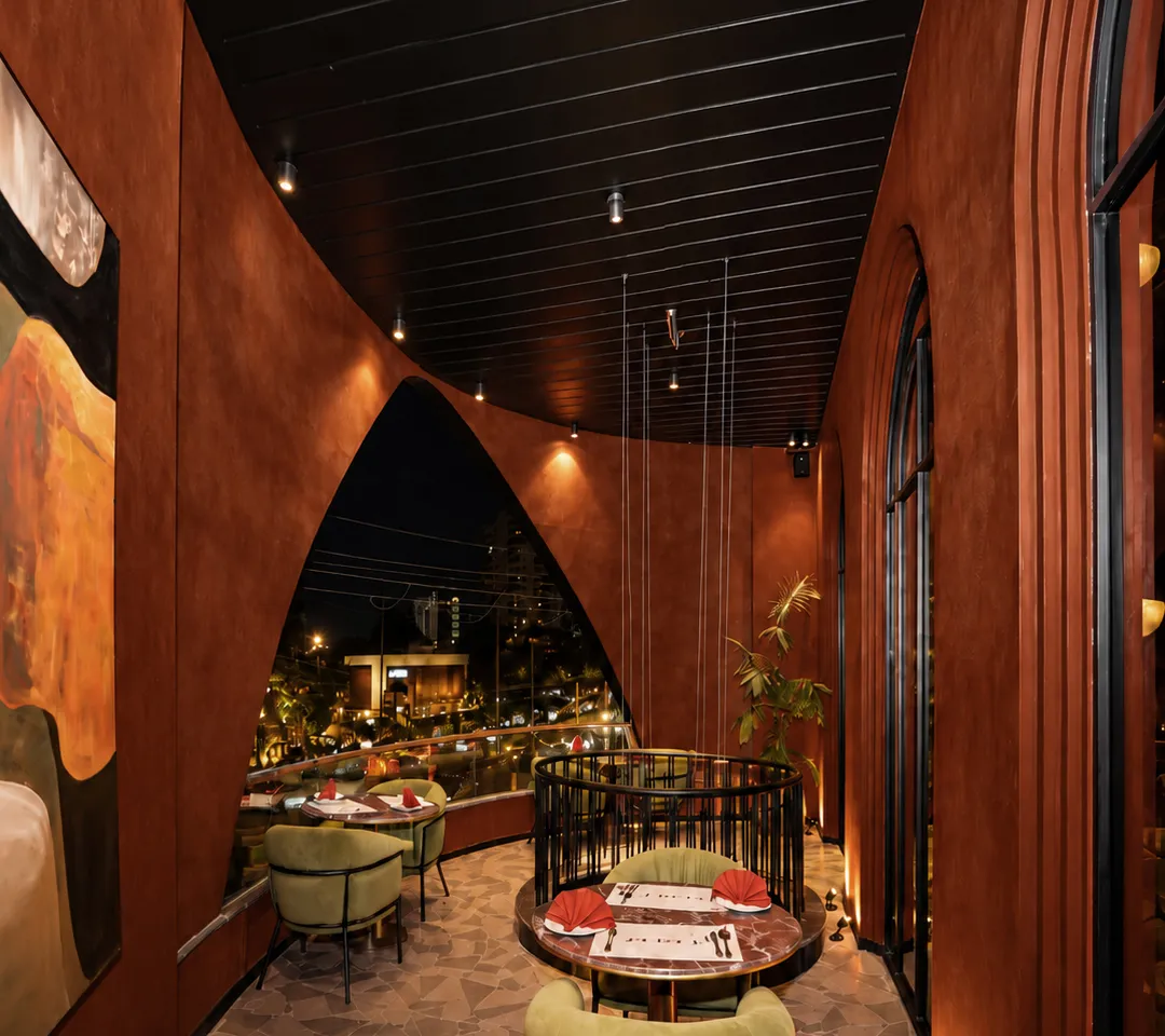 Terracotta gallery corridor with tables beside a tall arched opening