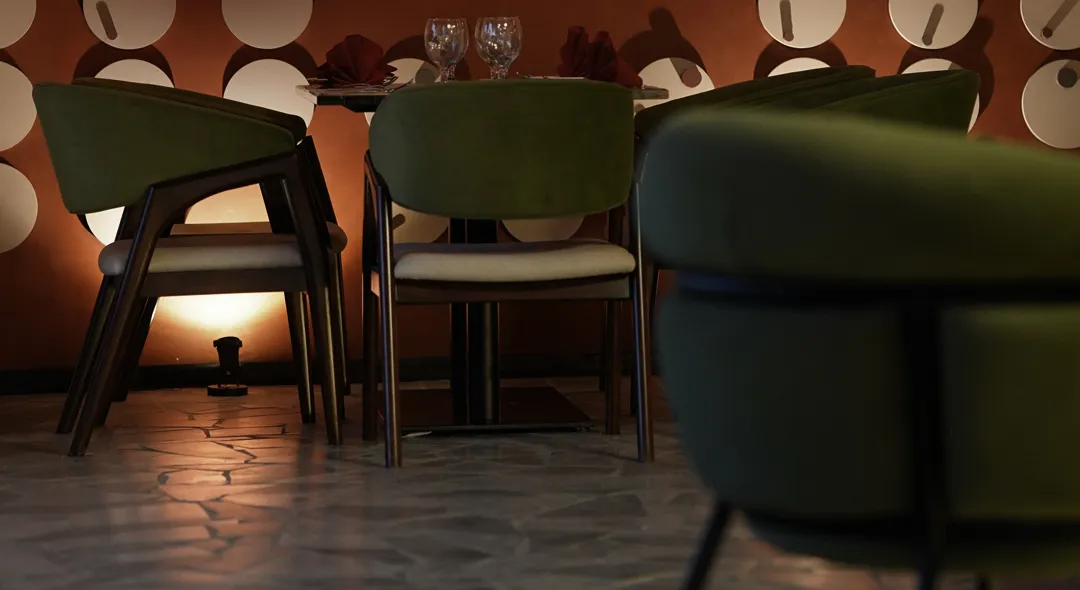 Olive chairs at a table against a wall of copper discs