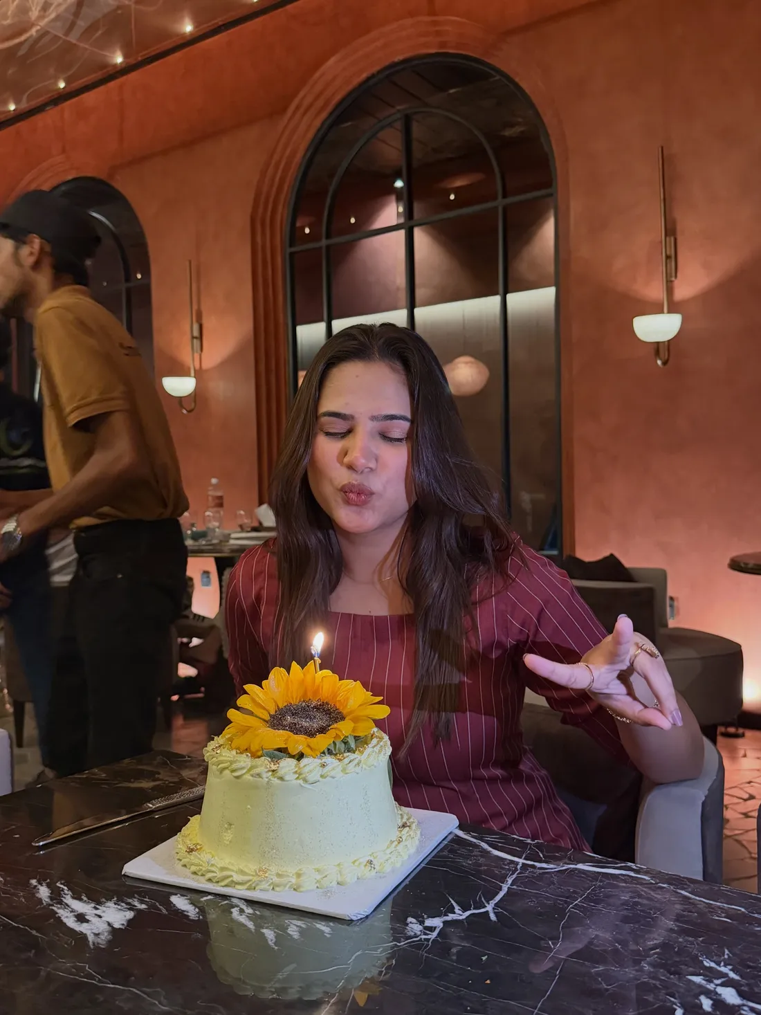 Guest blowing out a sunflower birthday cake
