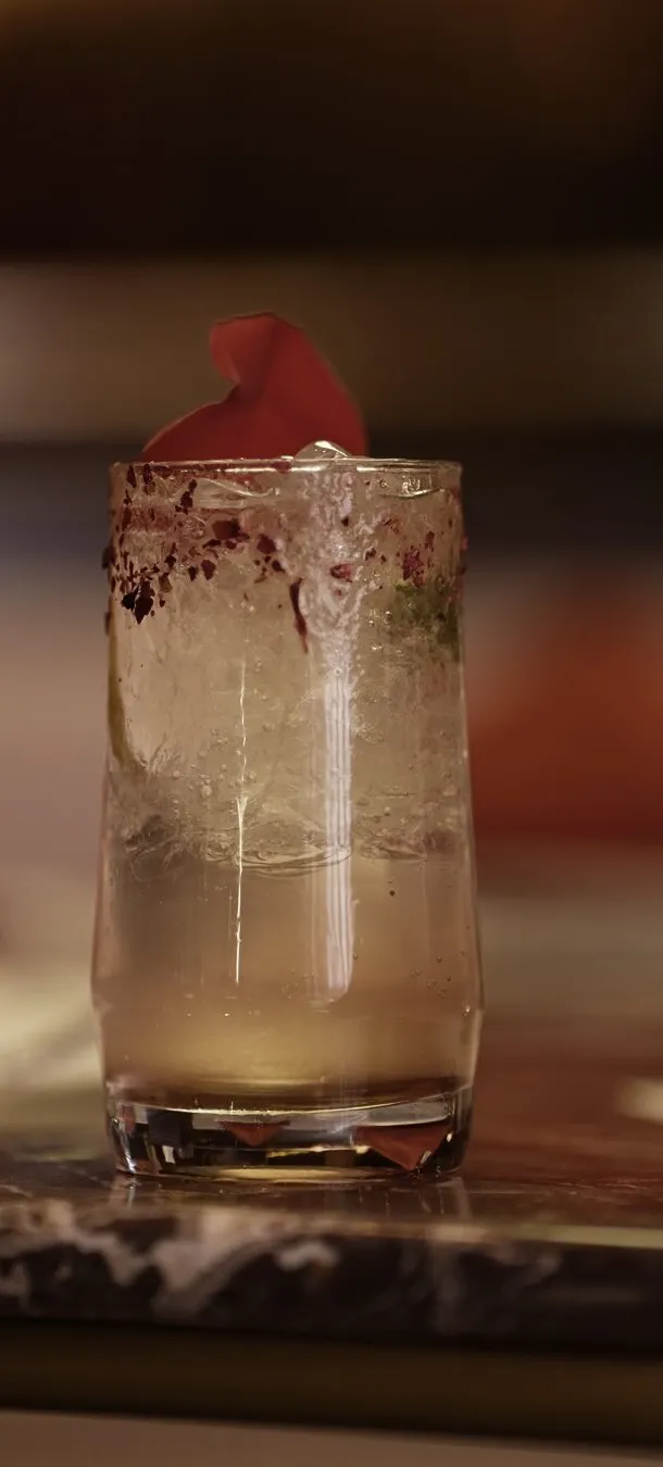 Sparkling mocktail with a rose petal on a marble bar
