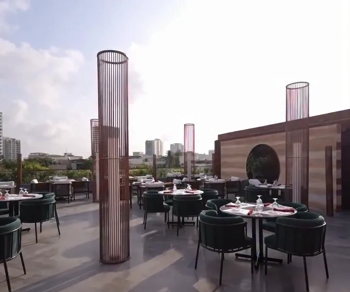Rooftop terrace by day with copper lantern columns and green velvet chairs